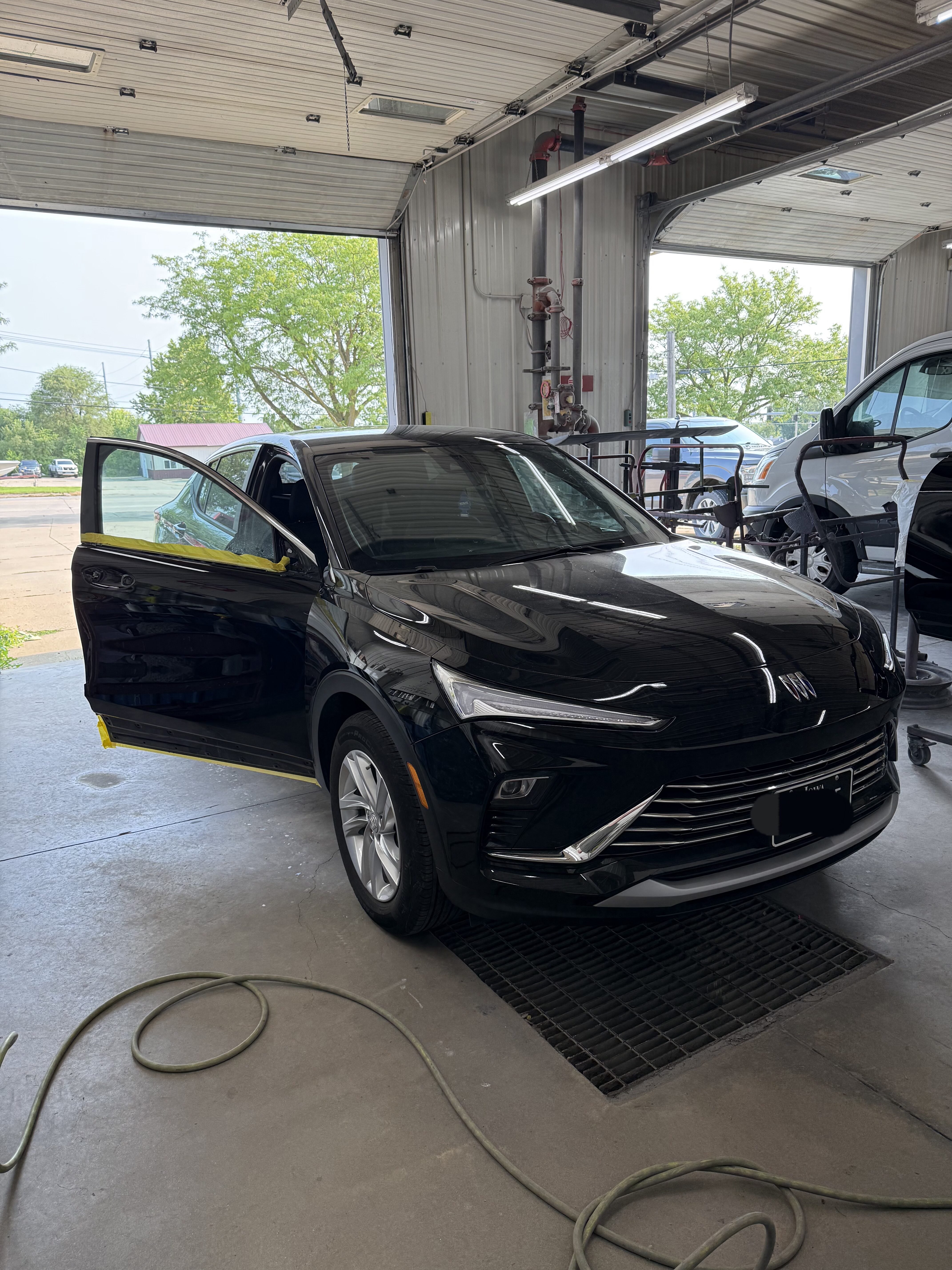 Black Buick SUV with open driver’s door inside Kelley’s Auto Body shop, highlighting expert auto body repair services, insurance collaboration, and quality vehicle restoration in Cedar Rapids.