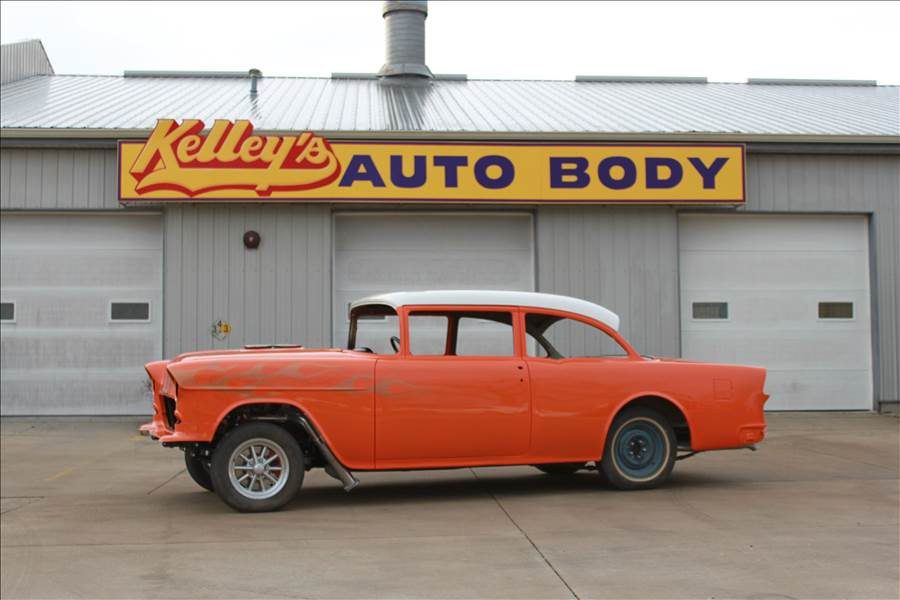 Classic orange and white vintage car in front of Kelley’s Auto Body shop with yellow and blue sign, representing trusted Cedar Rapids collision repair experts with over 50 years of experience.